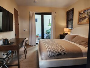 Una habitación de hotel con una cama, un escritorio, una silla, una lámpara y un cuadro en la pared.