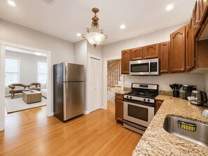 A modern kitchen with stainless steel appliances, wooden cabinets, and a granite countertop.