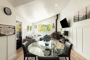 Un salon moderne avec une table à manger en verre, des fauteuils en cuir, un canapé et une cheminée.