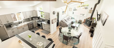 A spacious kitchen with modern appliances, a dining area with a glass table, and a cozy seating area with a fireplace.