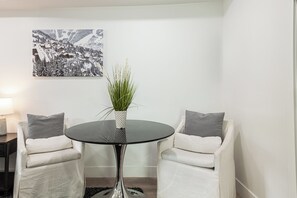 A modern room with a round table, two white armchairs, a potted plant, and a black and white painting on the wall. - Park City Ski Getaway | Private Hot Tub | Fireplaces | Sleeps 10 (Park City)