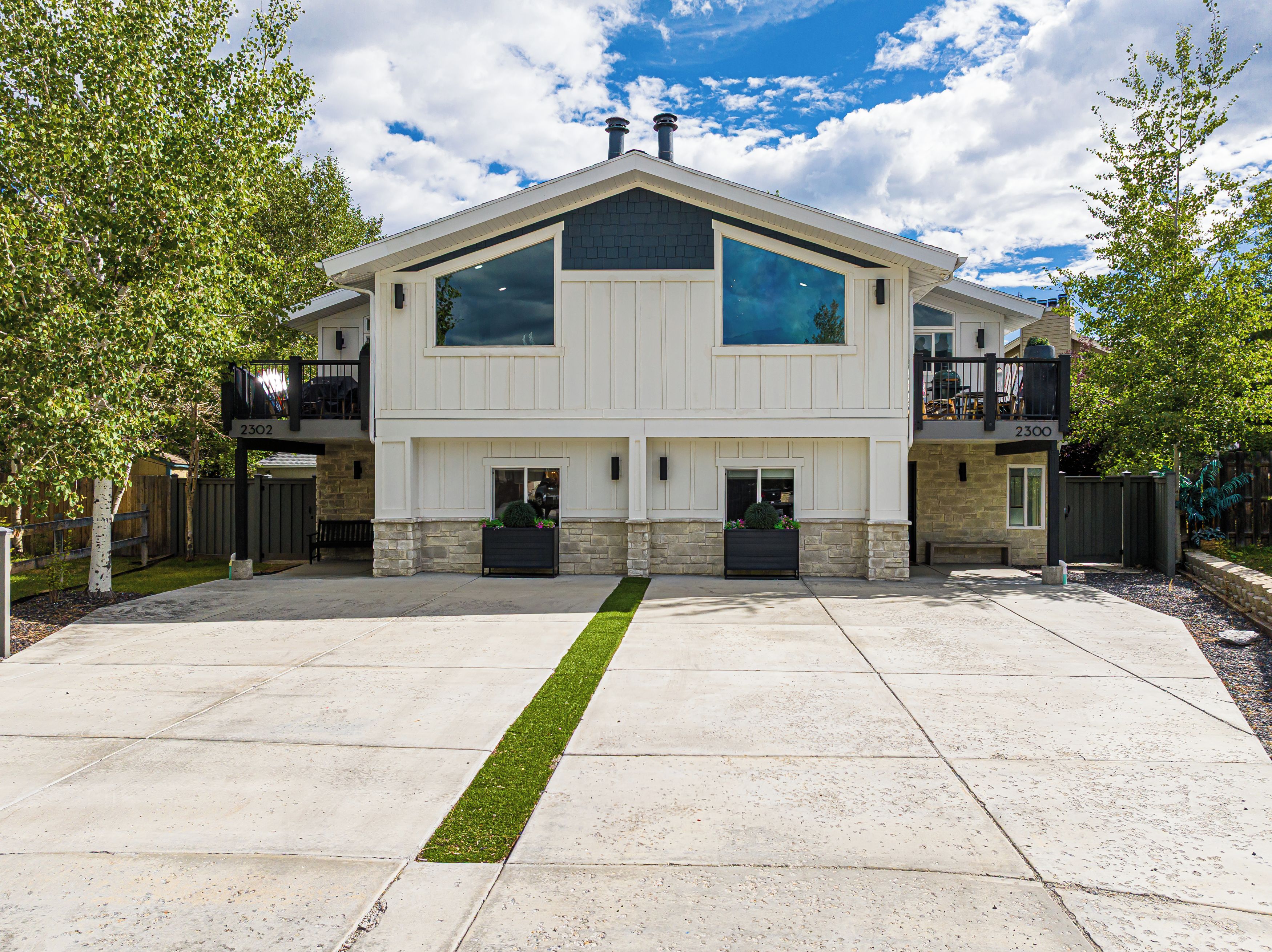 Une maison à deux étages avec une entrée centrale, un porche couvert et des fondations en pierre.