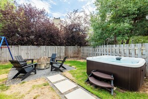A backyard with a hot tub, outdoor seating, and a wooden fence. - Park City Ski Getaway | Private Hot Tub | Fireplaces | Sleeps 10 (Park City)