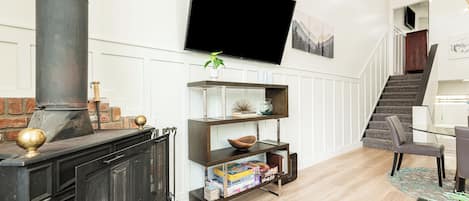 En stue med pejs, et fladskærms-tv ophængt på væggen og en trappe, der fører op til et andet niveau.