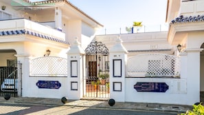 A gated entrance with a metal gate, white walls, and blue decorative tiles.