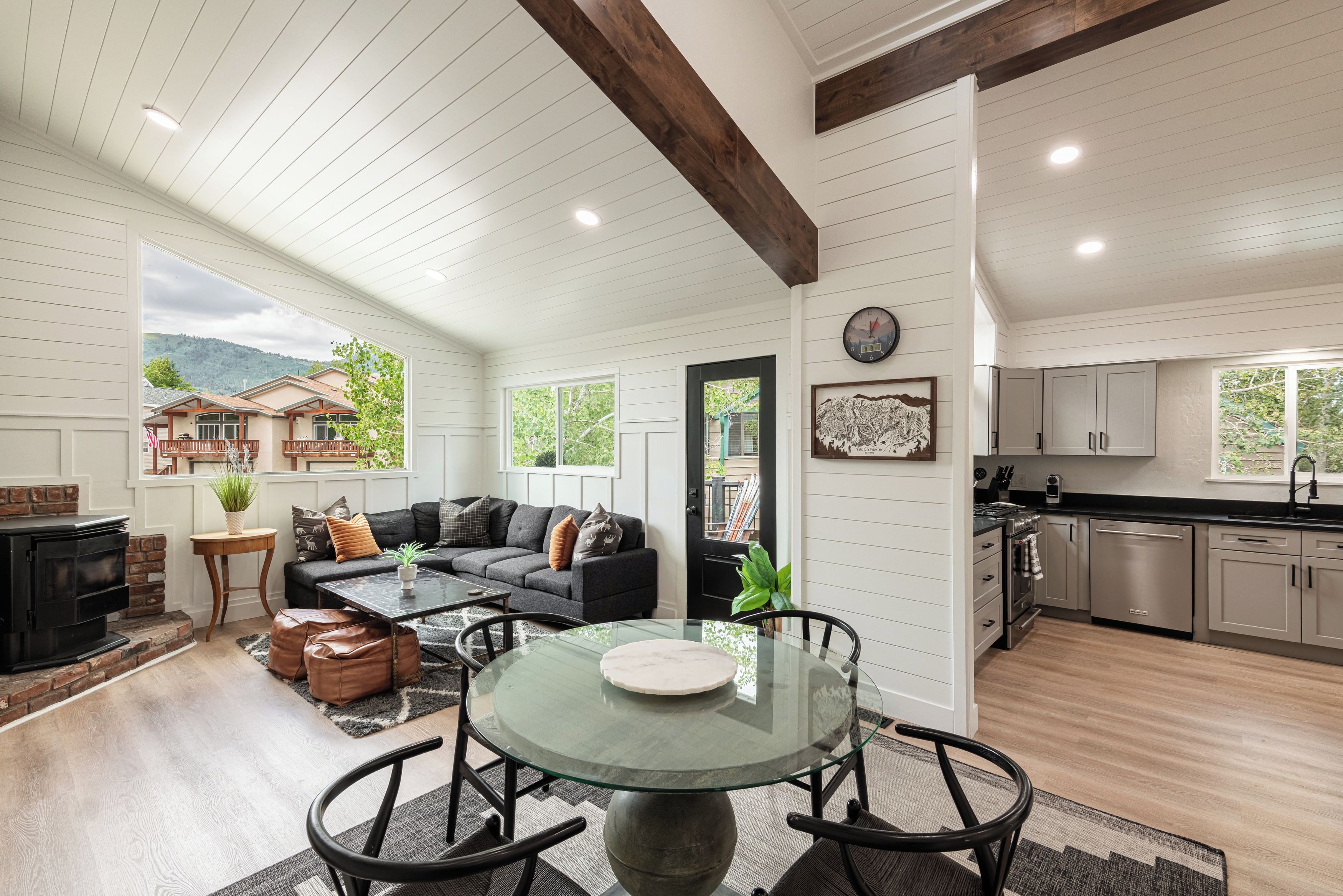A spacious living room with a fireplace, a dining area with a glass table, and a kitchen with modern appliances.