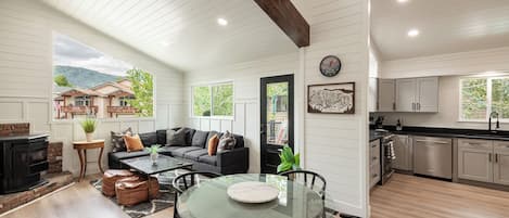 A spacious living room with a fireplace, a dining area with a glass table, and a kitchen with modern appliances.