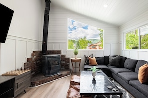 A living room with a fireplace, a sofa, a coffee table, and a view of a house through a window. - Spacious 4BR townhome for 10 in Park City's Prospector Square. (Park City)