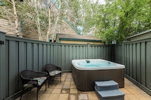 A backyard with a hot tub, two wicker chairs, and a wooden deck. - Spacious 4BR townhome for 10 in Park City's Prospector Square. (Park City)