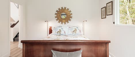 A bedroom with a wooden headboard, a sunburst mirror, and a bed with tiger-themed bedding.