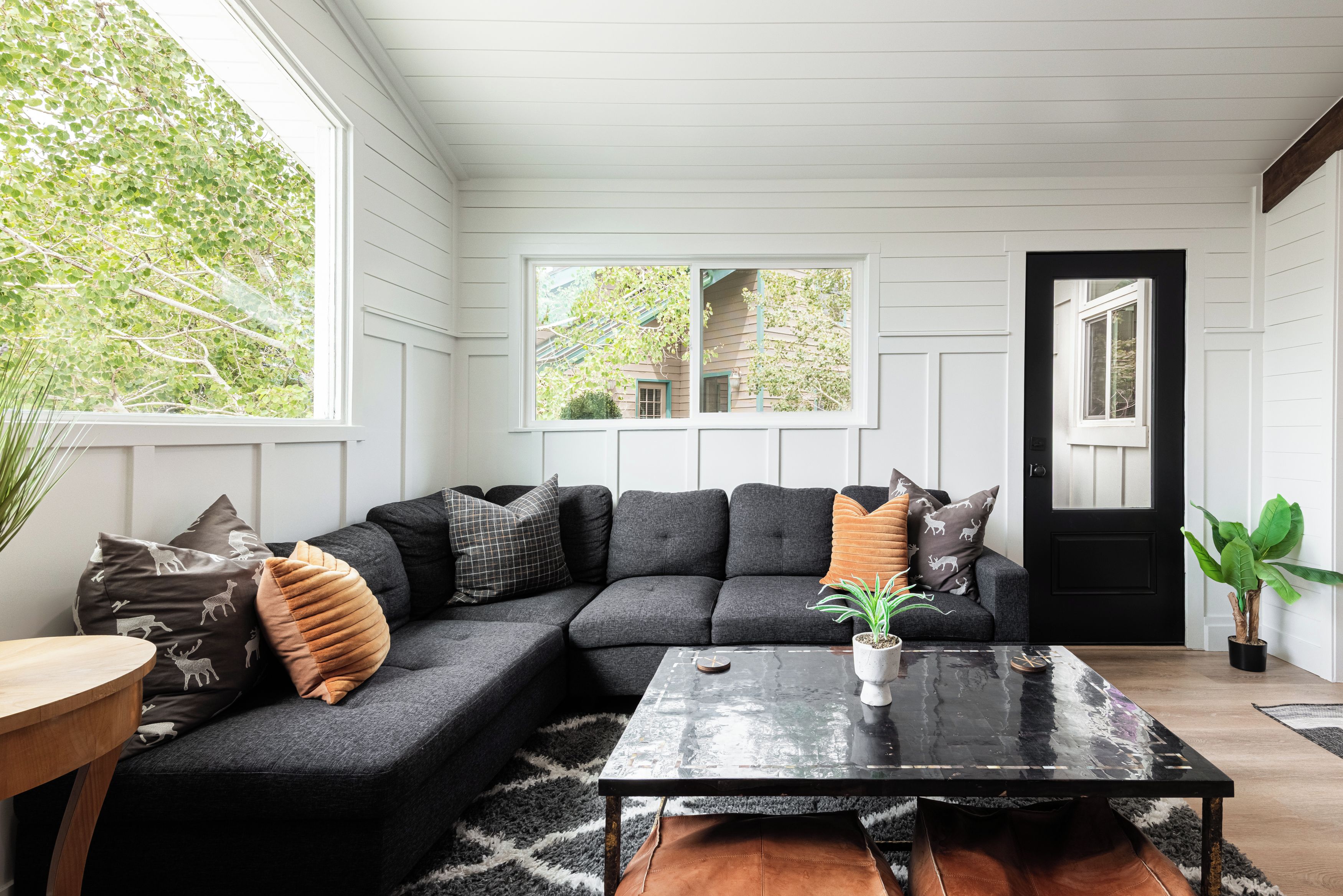 A modern living room with a sectional sofa, a coffee table, and a potted plant.