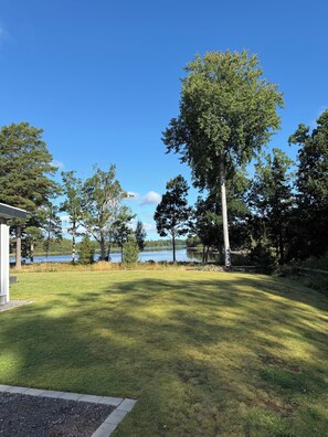 A grassy yard with a lake and trees. - Schweden-Auszeit: Lake Lodge mit Wintergarten, Sauna, Kamin & Boot direkt am See (Alsterbro ( Schweden))