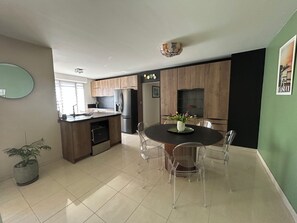 Eine moderne Küche mit Holzausbau, einem eingebauten Kühlschrank und einem Essbereich mit rundem Tisch und Stühlen.