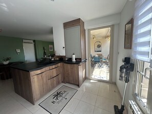 Eine moderne Küche mit einer Holzinsel, einem Essbereich mit Stühlen und Blick auf den Garten durch eine Glastür.