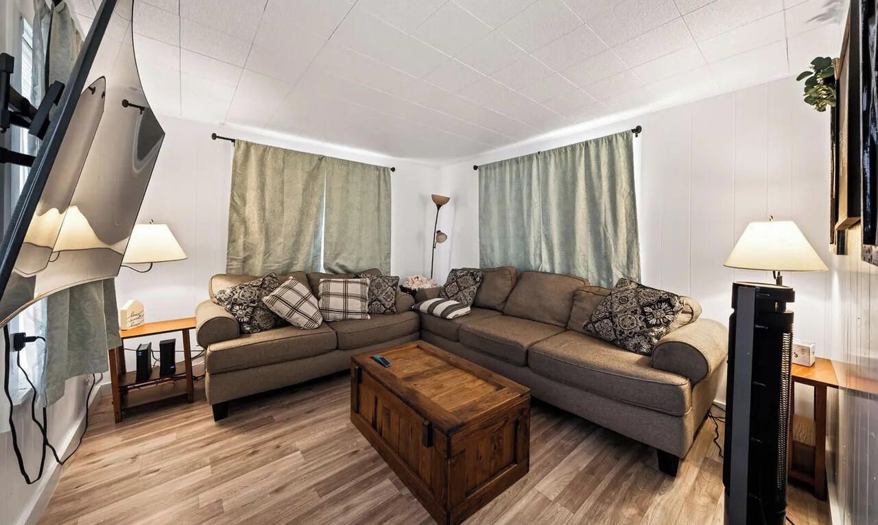 A living room with a sectional sofa, a wooden coffee table, and a television.