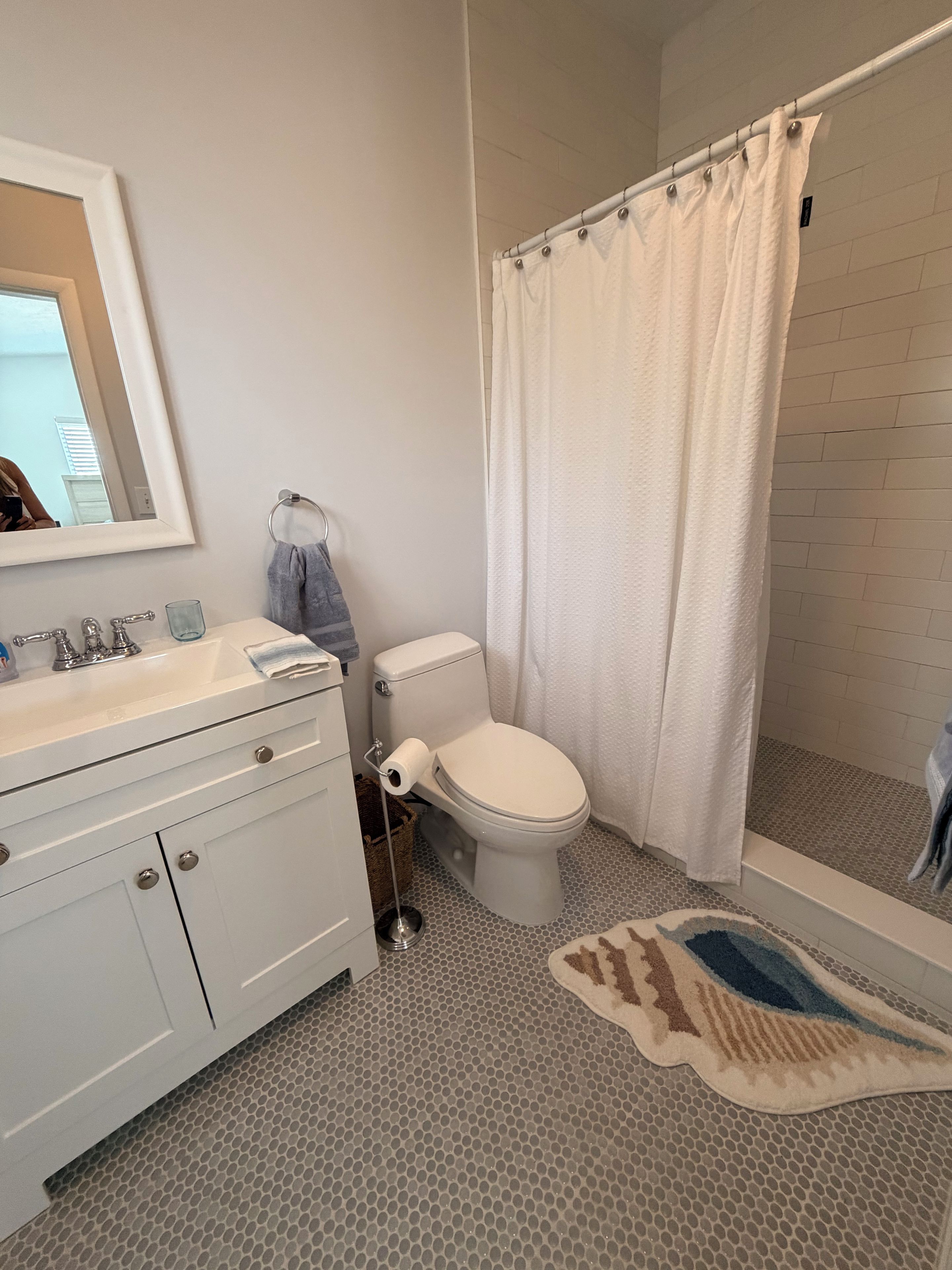 Une salle de bain avec un lavabo blanc, des toilettes et un rideau de douche.