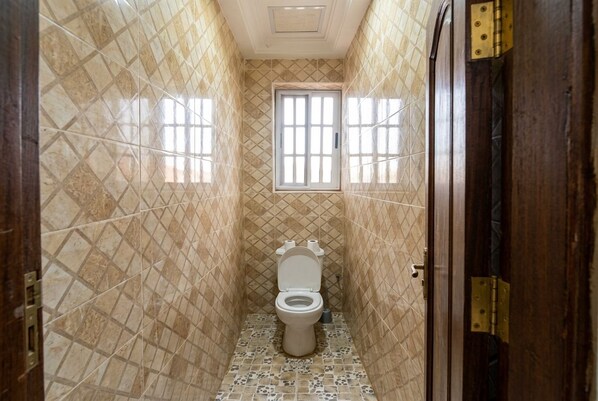 Ein schmales Badezimmer mit Toilette, Fenster und Tür.