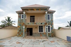 A two-story house with a balcony, a front door, and a small porch area. - A Downtown Gbetsile Studio Balcony + King Bed (Tema)