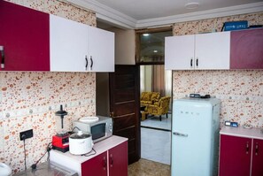 A kitchen with a microwave, blender, and a vintage Smeg refrigerator. - A Downtown Gbetsile Studio Balcony + King Bed (Tema)