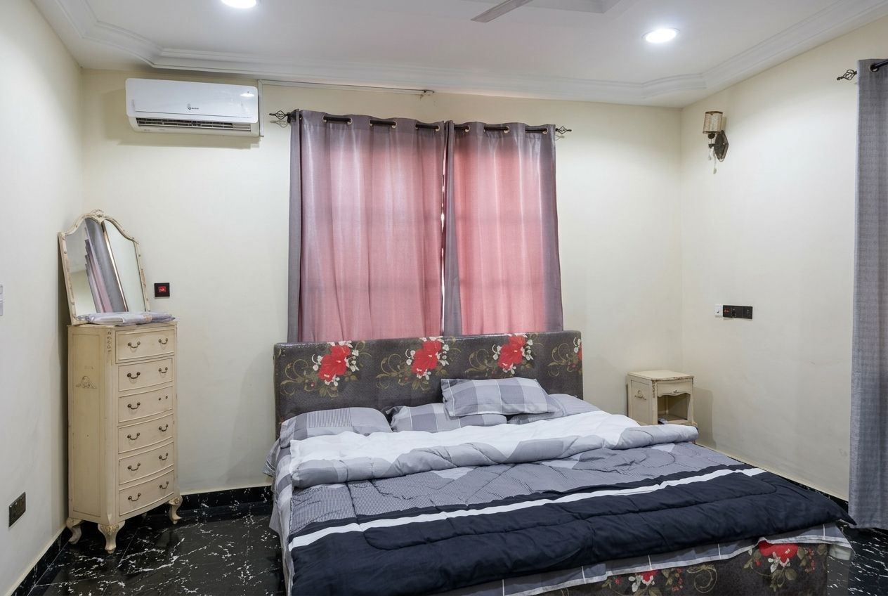Un dormitorio con cama, cómoda, aire acondicionado y mesita de noche.