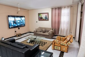 Ein Wohnzimmer mit Flachbildfernseher, Sofa, Couchtisch und einem gemusterten Teppich.