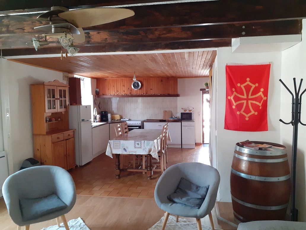 Et køkken med træskabe, et spisebord med stole og et rødt flag på væggen.