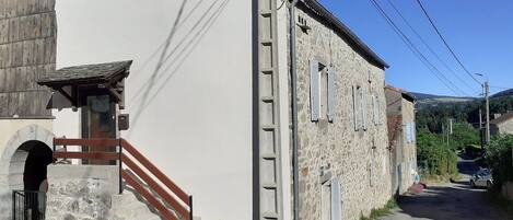 A building with a stone facade, a wooden staircase, and a paved street.