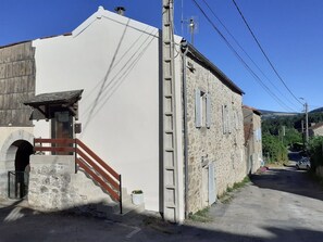 A building with a stone facade, a wooden staircase, and a paved street.