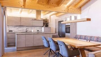 A modern kitchen with wooden beams, a dining area with a wooden table and chairs, and a built-in bench.