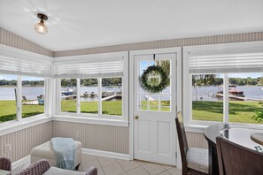 A room with a view of a lake, a door with a wreath, and a seating area with a table and chairs. - Lakefront Cottage w/ Sunset Views and Private Dock (Brooklyn)