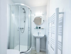 A modern bathroom with a glass-enclosed shower, a pedestal sink, and a towel rack. - The Stanley Arms Hotel by Guestz (Seascale)
