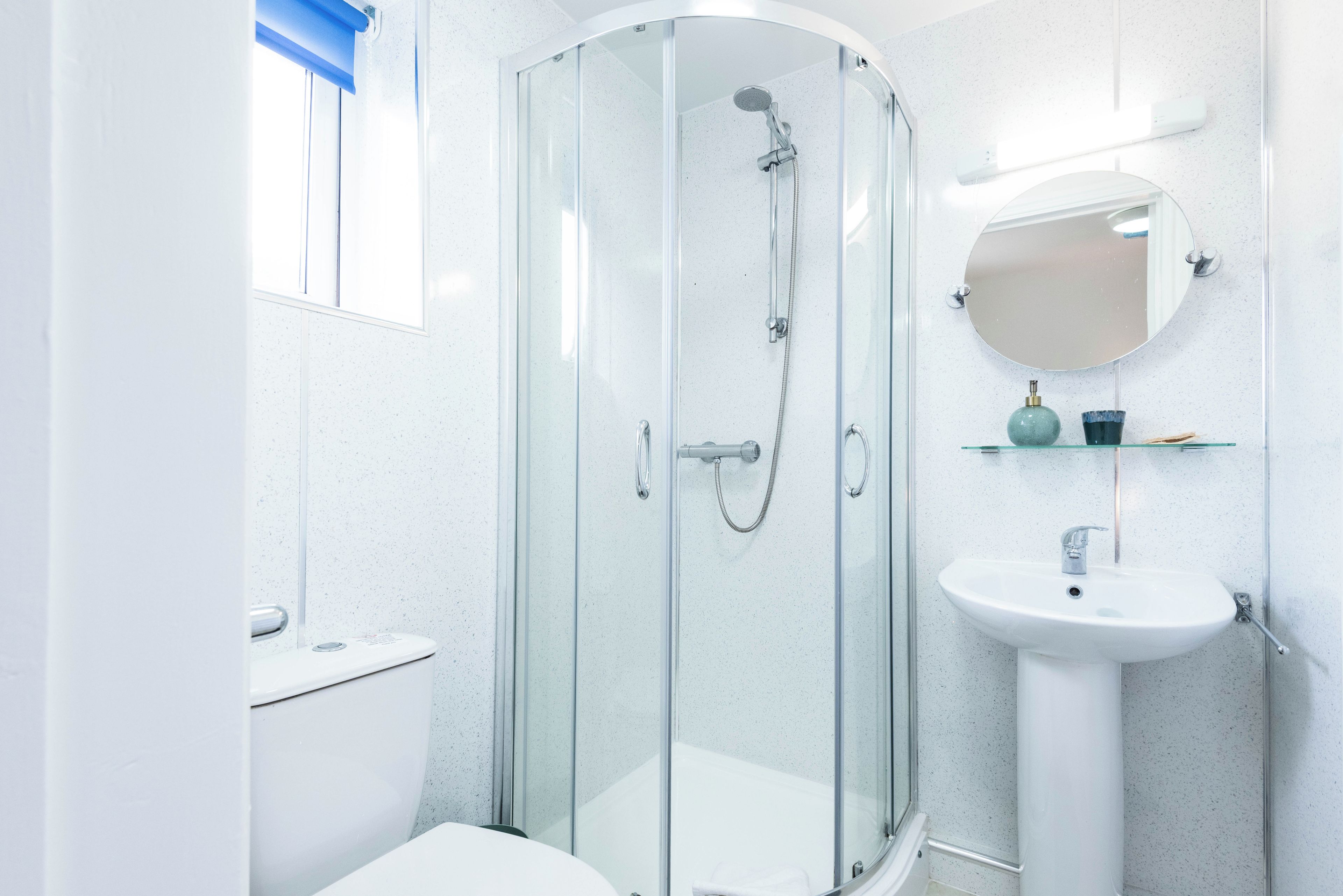 A modern bathroom with a glass-enclosed shower, a white sink, and a mirror above it.