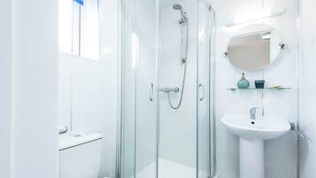 A modern bathroom with a glass-enclosed shower, a white sink, and a mirror above it.