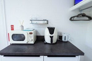 Een kitchenette met een magnetron, broodrooster en waterkoker op een zwart aanrecht.