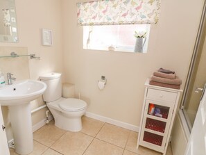 A bathroom with a toilet, sink, and a cabinet with a glass door. - The Byre (Ashbourne)