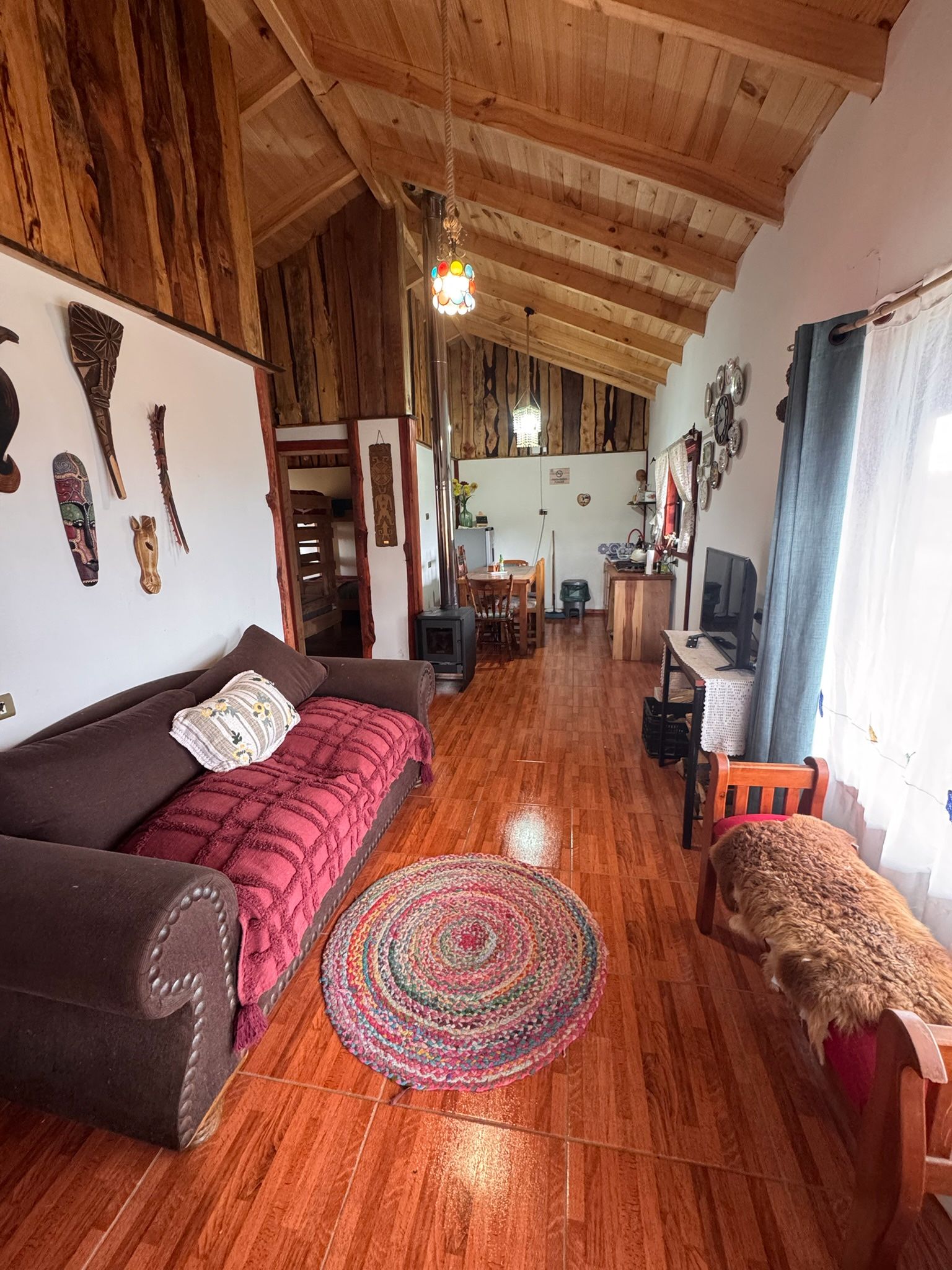 Una sala de estar acogedora con techo de madera, un sofá, un televisor y un perro.