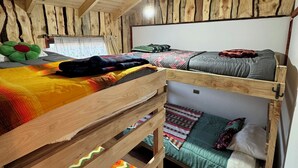 A bunk bed room with wooden walls and a sloped ceiling. - Soothing 2-bedroom cottage perfect for a relaxing getaway (Chile)