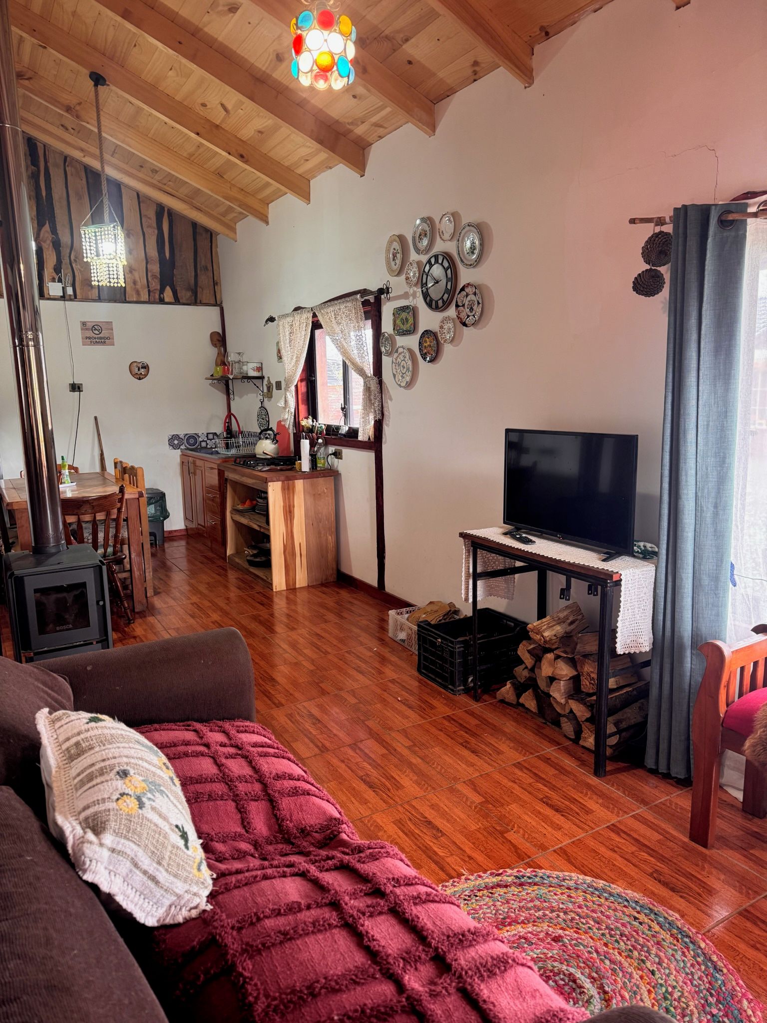 Una sala de estar acogedora con televisor, muebles de madera, chimenea y comedor.