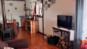 Una sala de estar acogedora con televisor, muebles de madera, chimenea y comedor.