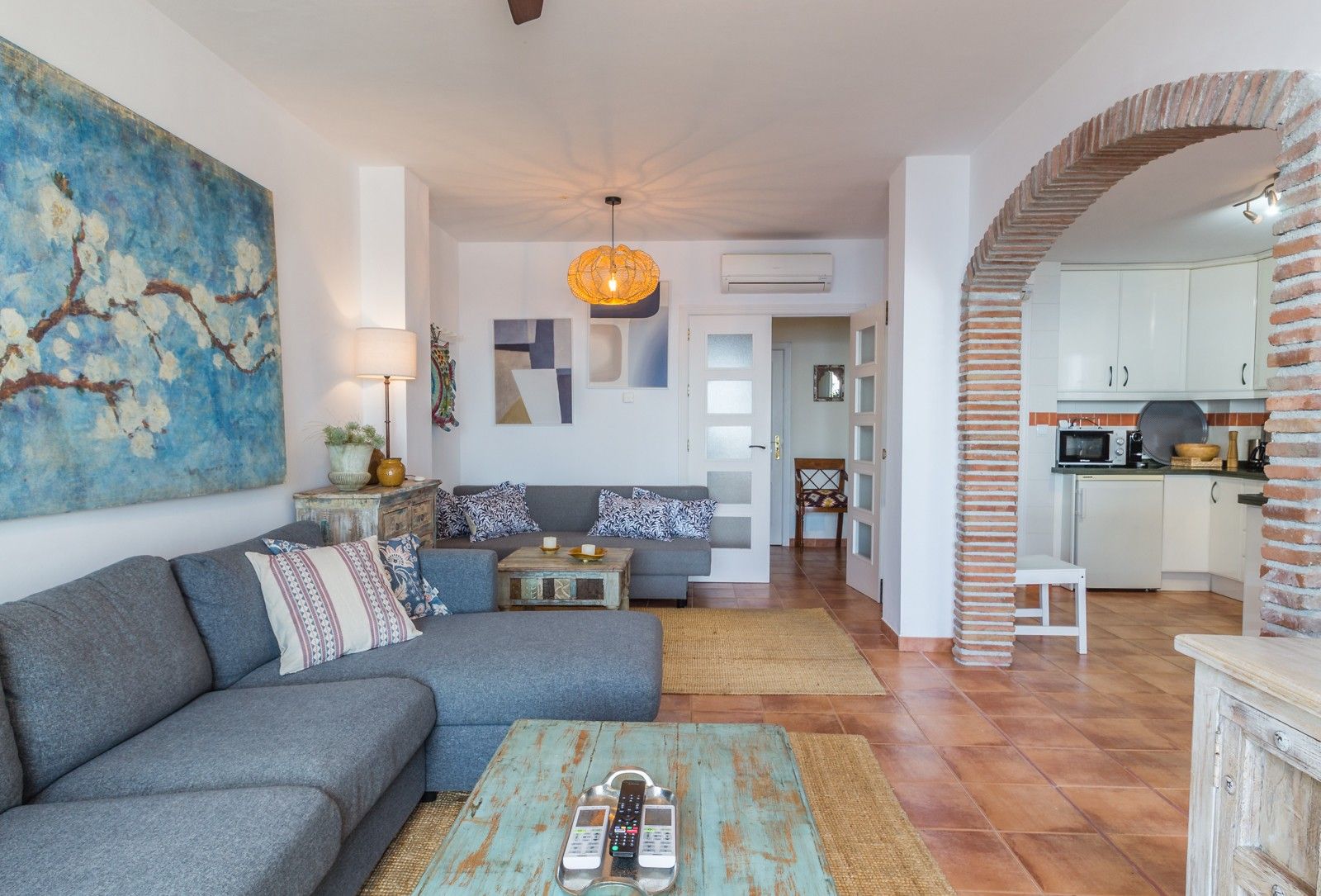 A living room with a sofa, a coffee table, and a painting on the wall.