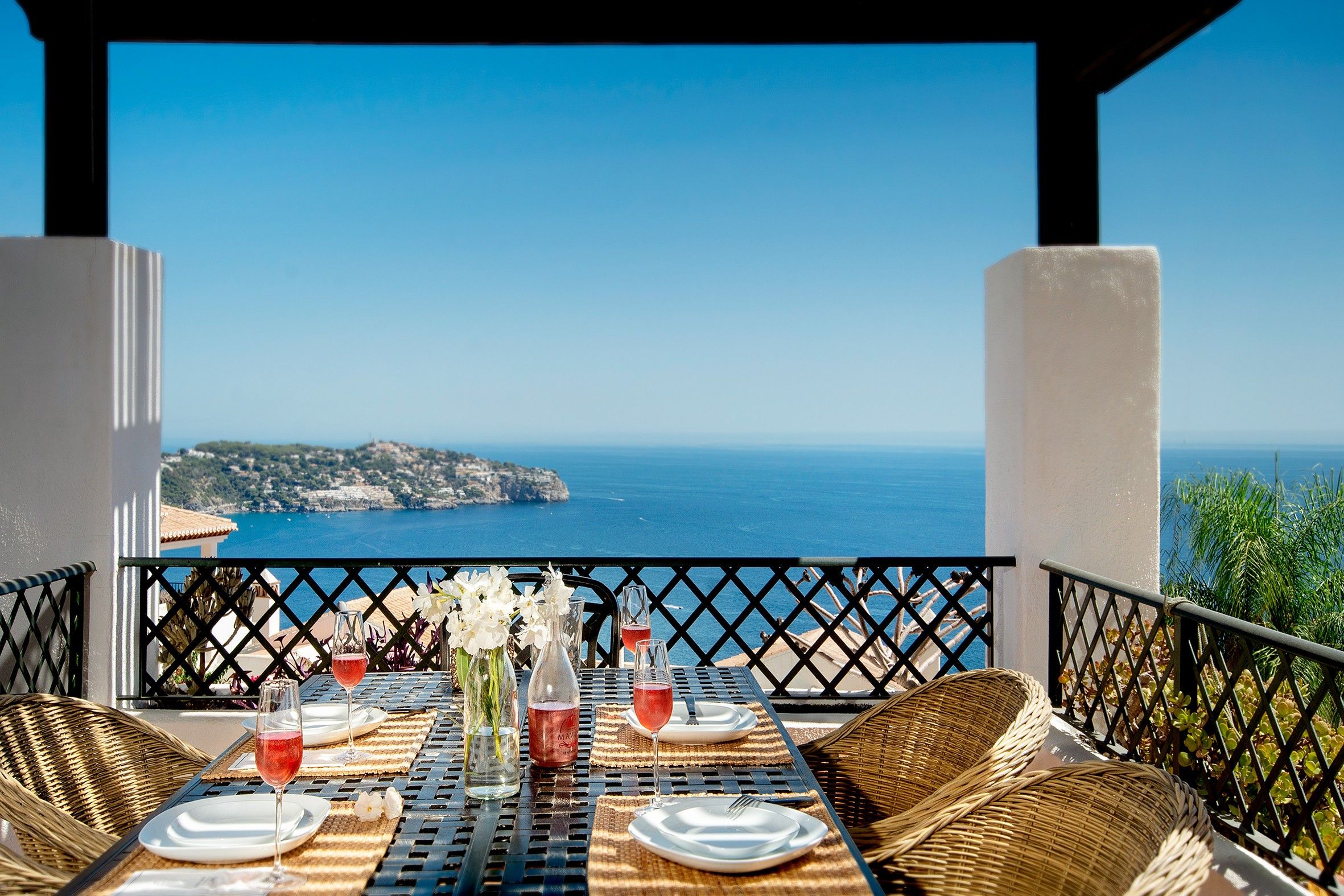 A table set for two with a view of the sea and a coastal landscape.