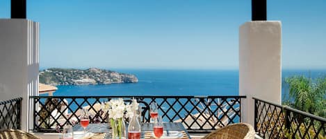 A table set for two with a view of the sea and a coastal landscape.