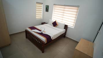 Habitación de hotel con cama, dos mesitas de noche, ventana con persianas, un cuadro en la pared y un armario de madera.