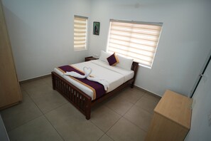 A hotel room with a bed, two bedside tables, a window with blinds, a picture on the wall, and a wooden wardrobe. - Vaga Dreams (Vagamon)