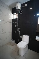 A bathroom with a toilet, a shower unit, and a marble-tiled wall.