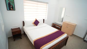 A bedroom with a bed, a nightstand, a dresser, a window with blinds, and a painting on the wall.