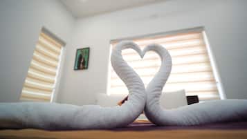 Una habitación con una cama, una disposición de toallas en forma de corazón y un cuadro en la pared.
