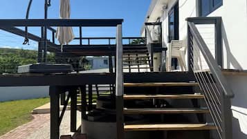 A wooden outdoor staircase leading to a covered area with a metal railing and a white umbrella.