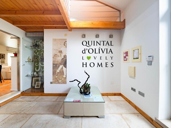 Een ruimte met een houten plafond, een glazen tafel met een sculptuur en een muur met een poster.