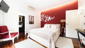 A bedroom with a bed, a red chair, a white desk, and a wall-mounted TV. - Country House 'D’Olívia Lovely Homes -Casa Olívia' with Shared Garden, Wi-Fi and Air Conditioning (Cela)